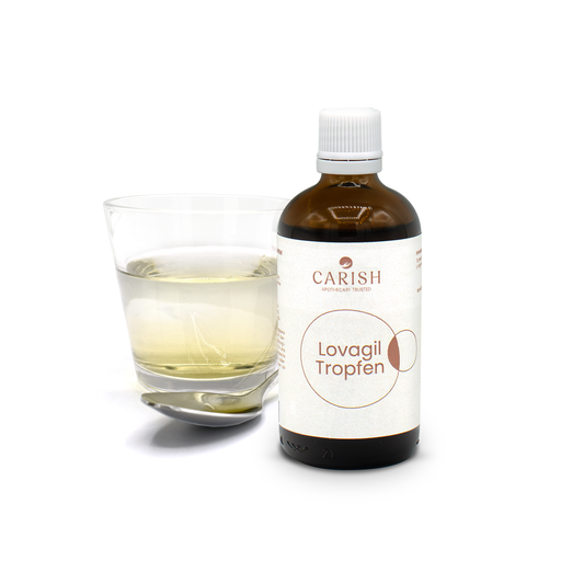 Im Vordergrund die dunkelbraune Flasche der Lovagil Tropfen, im Hintergrund liegt ein Löffel und steht ein Glas mit den Tropfen zur Ansicht.