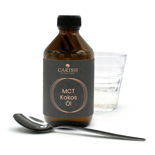 Das MCT Kokosöl in einer dunkelbraunen Glasflasche. Im Vordergrund ein Löffel mit dem Öl zur Ansicht, im Hintergrund ein Glas mit dem Öl.