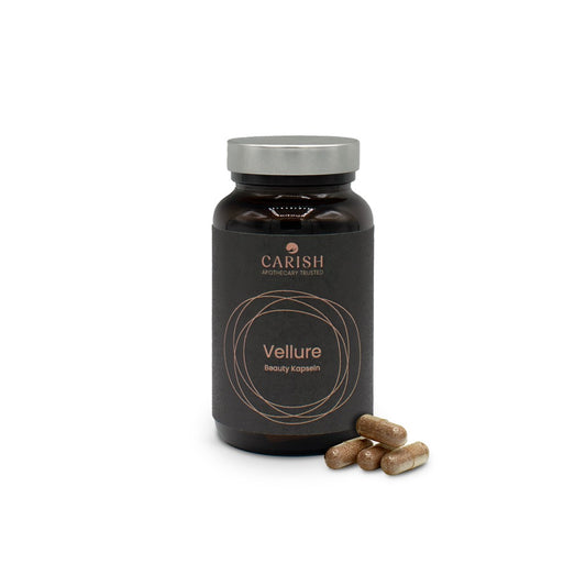 Abbildung der Vellure Schönheitskapseln im braunen Glasbehälter mit verschraubbarem silbernen Deckel und Beschreibung auf einem schwarzen Etikett. Im Vordergrund liegen 4 braune Kapseln zur Ansicht.