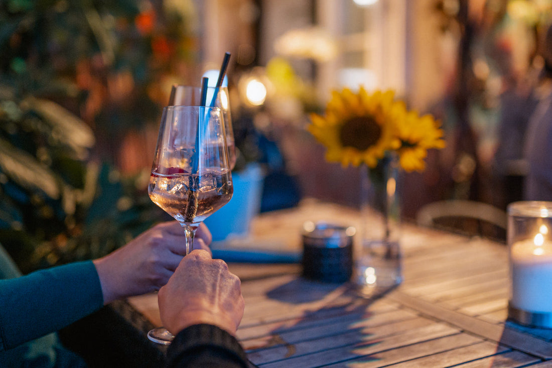Zwei Hände haben jeweils ein Weinglas in der Hand und stoßen an.