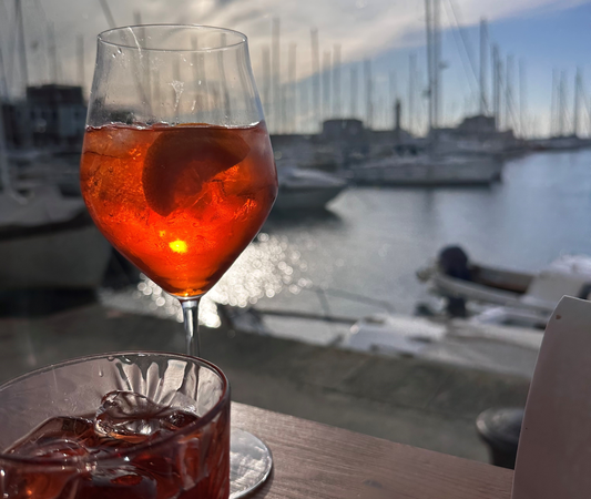 2 Cocktails stehen auf einem Tisch, im Hintergrund sieht man einen Hafen mit