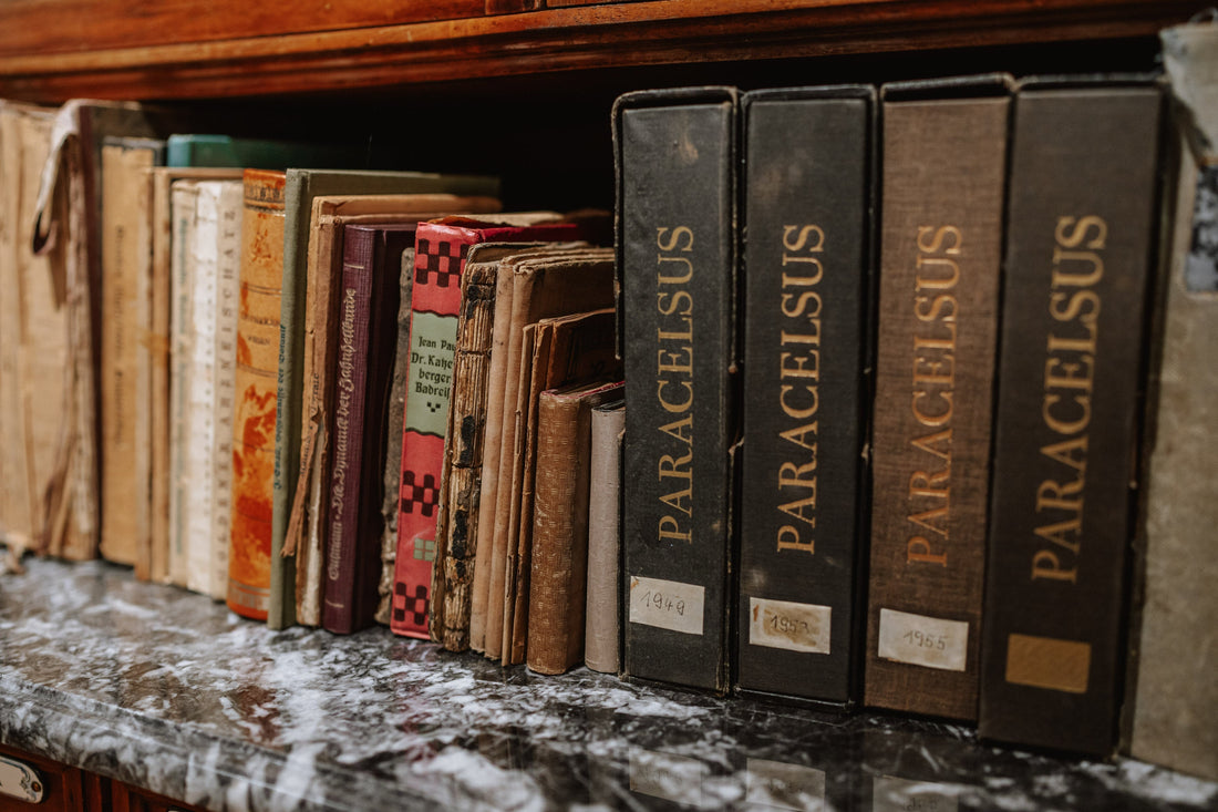 Alte Apothekenbücher stehen mit dem Buchrücken in einem Regal.