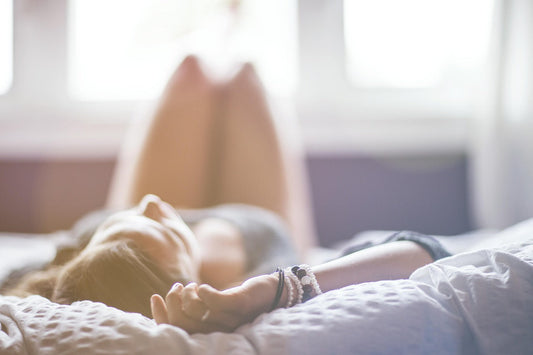 Eine Frau liegt in einem Bett und wurde von hinten fotografiert. 