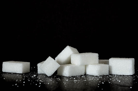 Einige Zuckerwürfel liegen auf einem schwarzen Tisch.