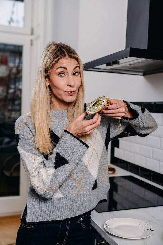 Nina Milenkovics steht in einer Küche mit einem gesunden Wrap in der Hand. 