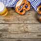 Auf einem alten Holztisch steht ein Krügerl Bier und 2 Brezen liegen daneben. 
