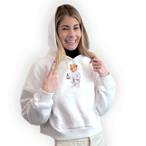 Nina Milenkovics trägt den weißen Apothekerbär Hoodie von Baron Filou und hat die Kapuze auf dem Kopf. 