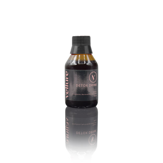Durchsichtige braune Glasflasche mit schwarzem Kunststoffdeckel und Etikett mit der Beschreibung des Detox Drinks.  